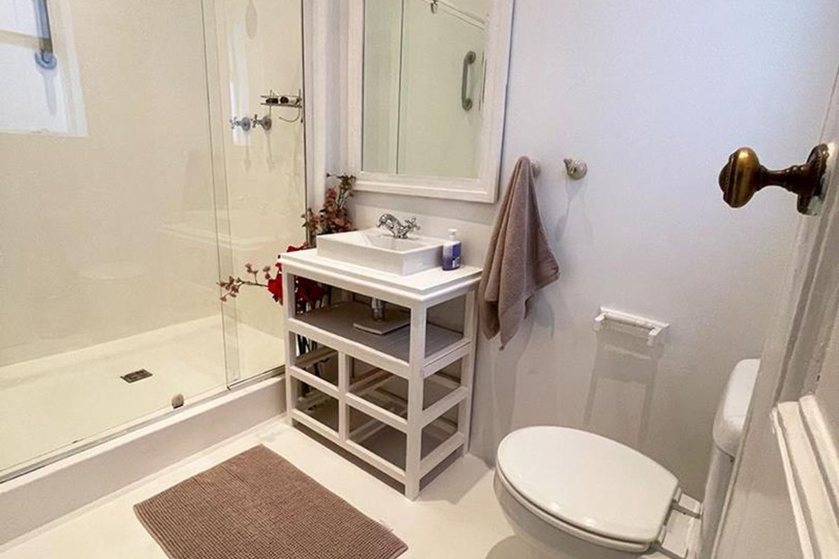 A clean and functional bathroom featuring a glass-enclosed shower, a modern vanity basin with a mirror, and a standard toilet.