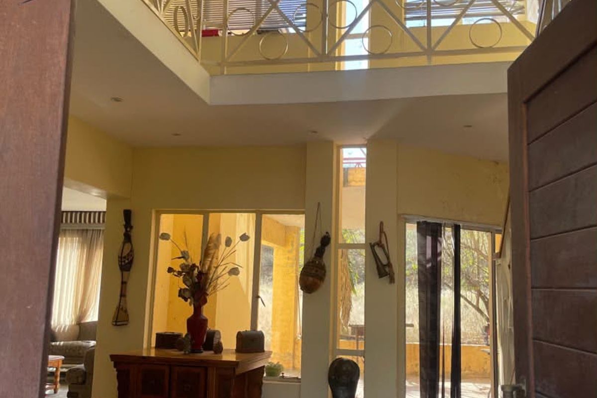 Spacious double-volume entrance hall featuring a mezzanine level with decorative metal balustrading, tiled flooring, and abundant natural light through large windows.