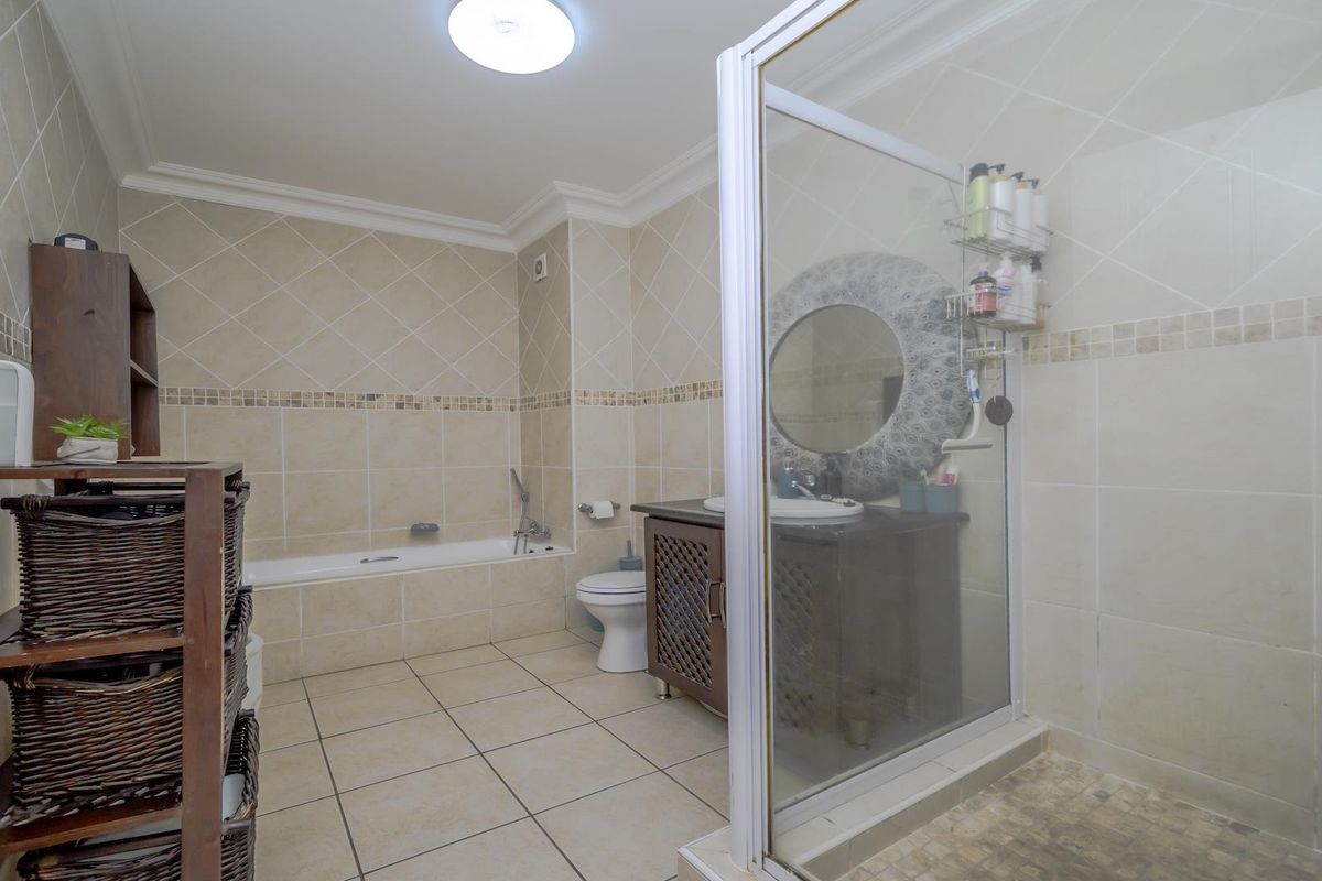 A spacious bathroom featuring a bathtub, a separate shower enclosure, a vanity cabinet with a basin, and neutral ceramic wall and floor tiling.