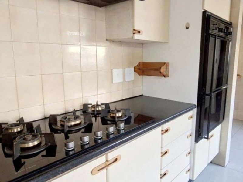 A functional kitchen featuring a built-in gas hob, integrated oven, and tiled backsplash with ample cabinetry for storage.