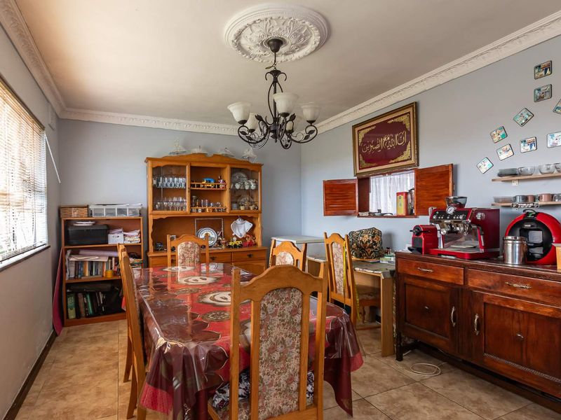 A dining room featuring tiled flooring, decorative ceiling rose, and classic cornice detailing, providing a functional space for family meals.