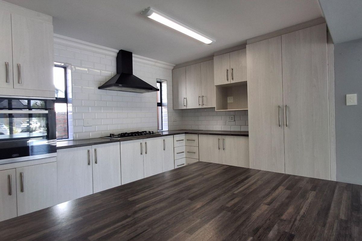 Modern kitchen featuring light wood-grain cabinetry, subway tile backsplash, dark laminate countertops, and integrated appliances including a gas hob and oven.