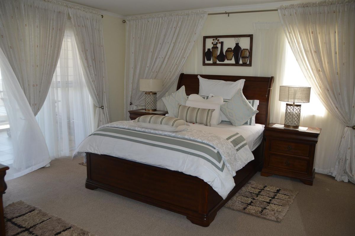 A well-maintained bedroom featuring neutral carpeting, soft window treatments, and access to an outdoor area through a sliding glass door.