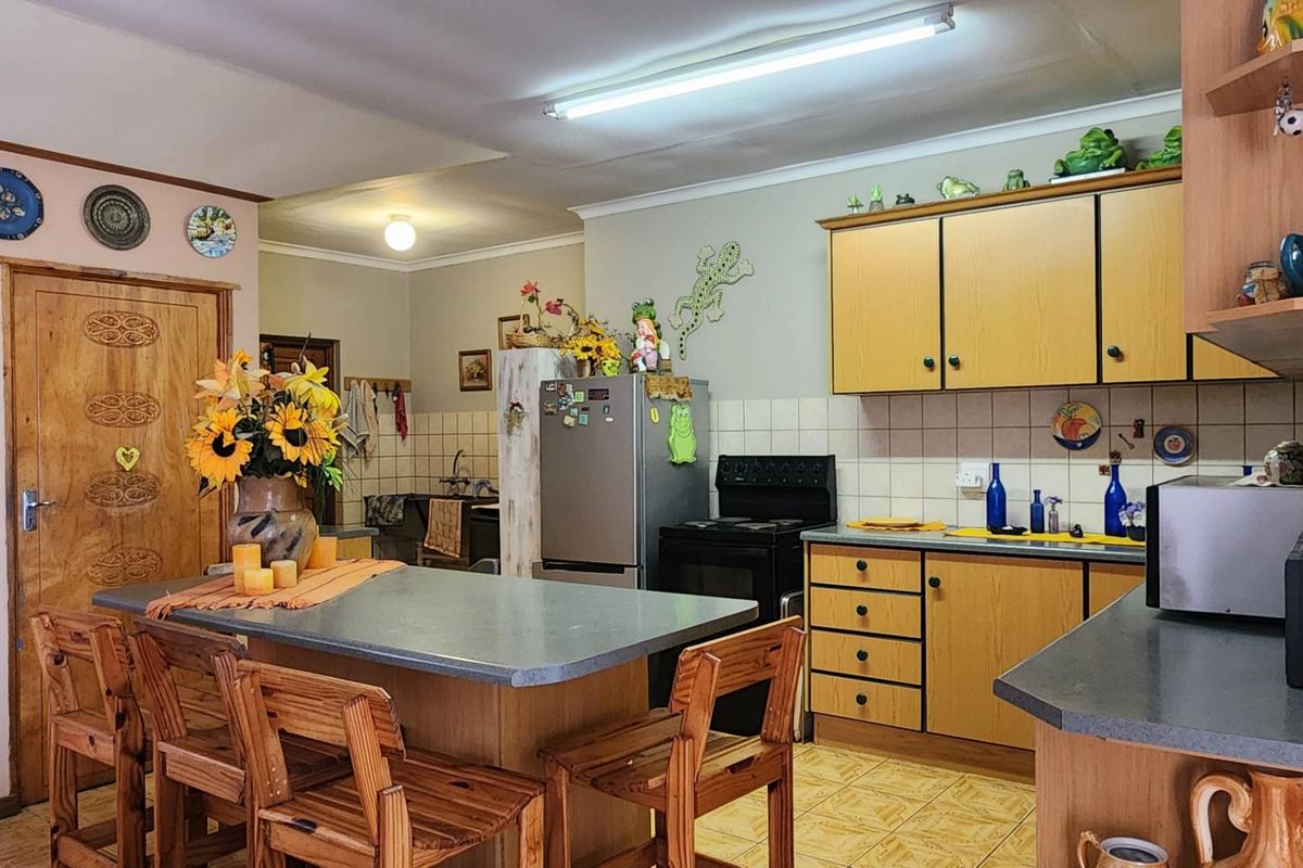 A functional kitchen featuring wooden cabinetry, a central island with seating, and tiled flooring, offering a traditional layout with ample storage space.