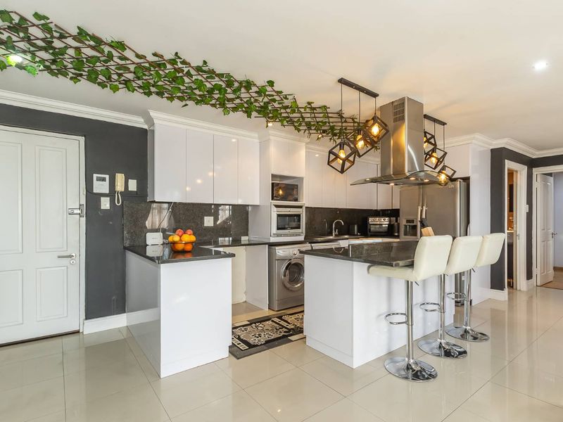 Modern kitchen featuring white cabinetry, granite countertops, integrated appliances, and a breakfast bar, creating a functional and stylish culinary space.