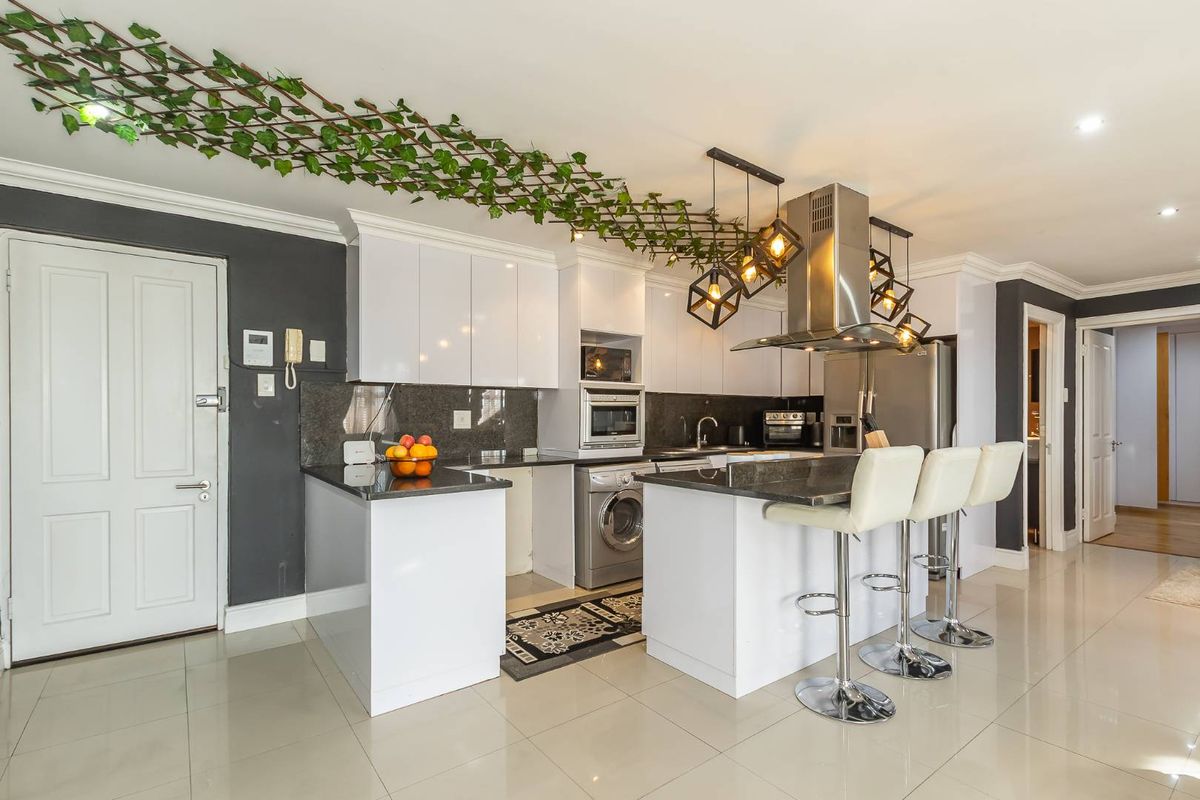 Modern kitchen featuring white cabinetry, granite countertops, integrated appliances, and a breakfast bar, creating a functional and stylish culinary space.