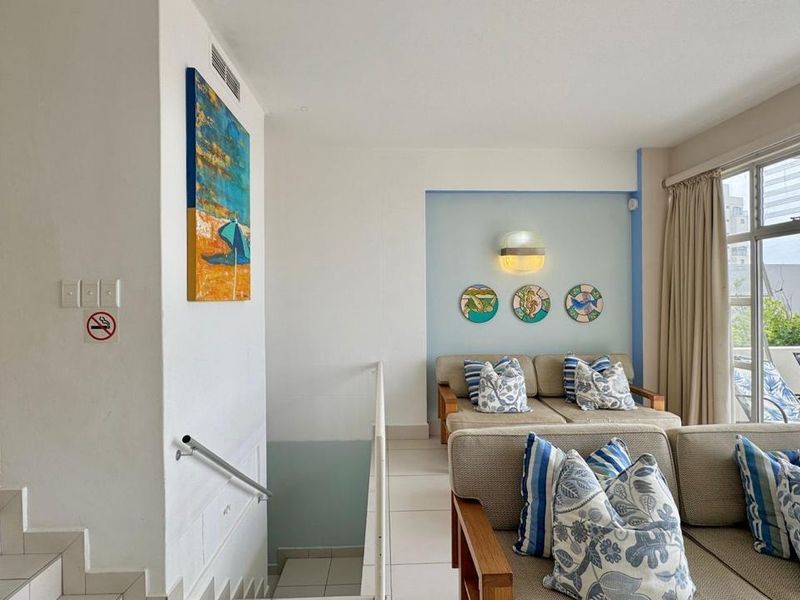 A bright living area featuring tiled flooring, a staircase with a metal handrail, and a sliding glass door leading to an outdoor space.
