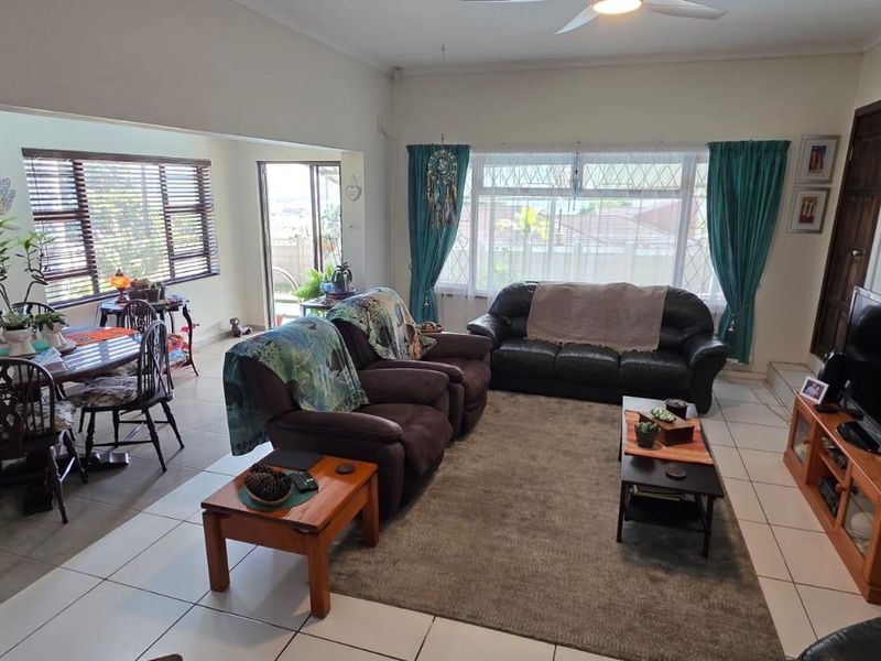 Spacious open-plan living and dining area featuring tiled flooring, a ceiling fan, and large windows providing ample natural light.