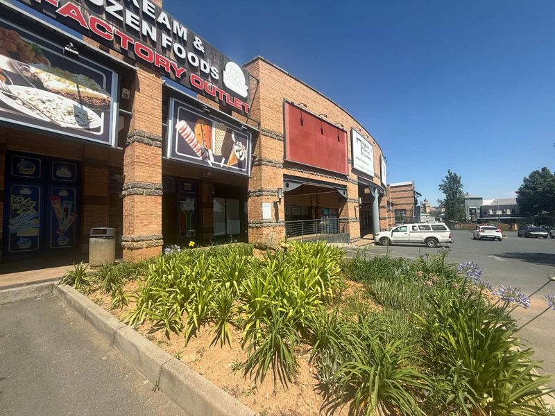 Front exterior view of a commercial building featuring brick facade, integrated signage, and a landscaped garden bed adjacent to the parking area.