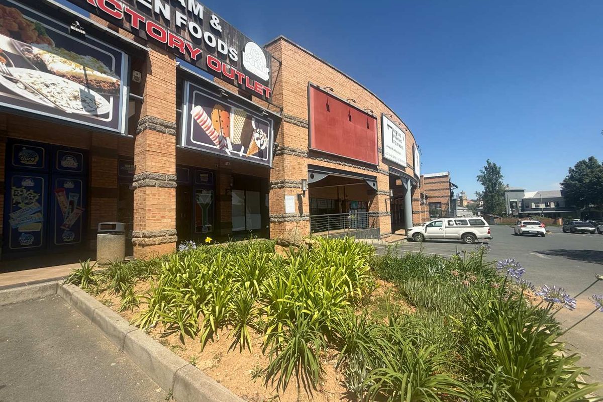 Front exterior view of a commercial building featuring brick facade, integrated signage, and a landscaped garden bed adjacent to the parking area.