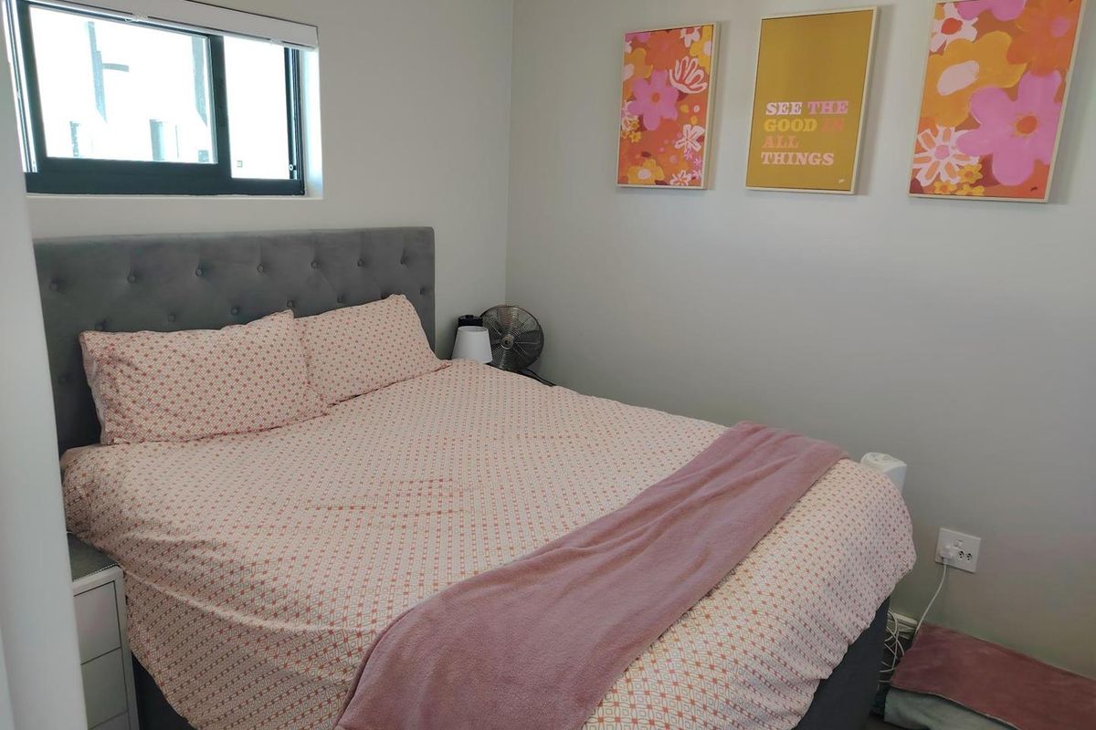 A well-maintained bedroom featuring neutral wall tones, a sliding window for natural light, and standard electrical fixtures.