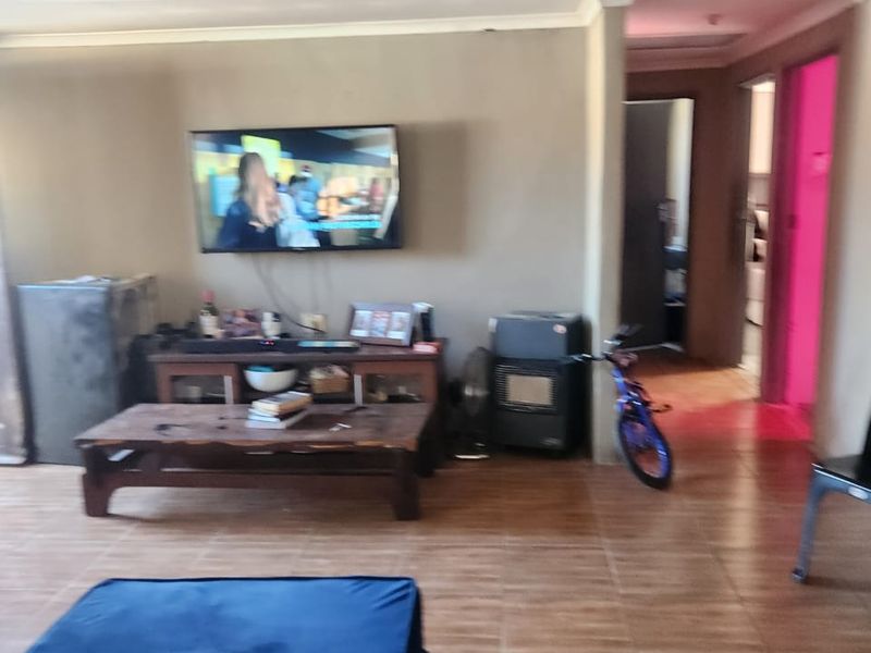 A living room area featuring tiled flooring and a recessed ceiling design, providing a functional space with access to adjacent rooms.