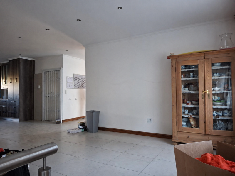 Open plan living area featuring tiled flooring, recessed downlights, and a view into the adjacent kitchen and hallway.