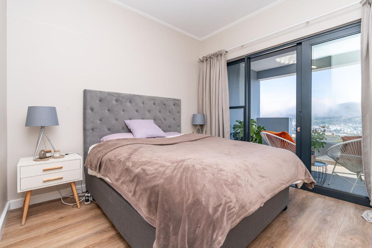 A well-maintained bedroom featuring laminate flooring and large sliding glass doors that provide access to a private balcony with scenic views.