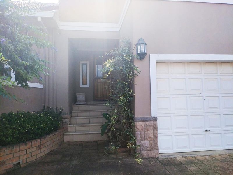 Front entrance of the house featuring a single garage, stone cladding accents, tiled steps, and a timber front door.