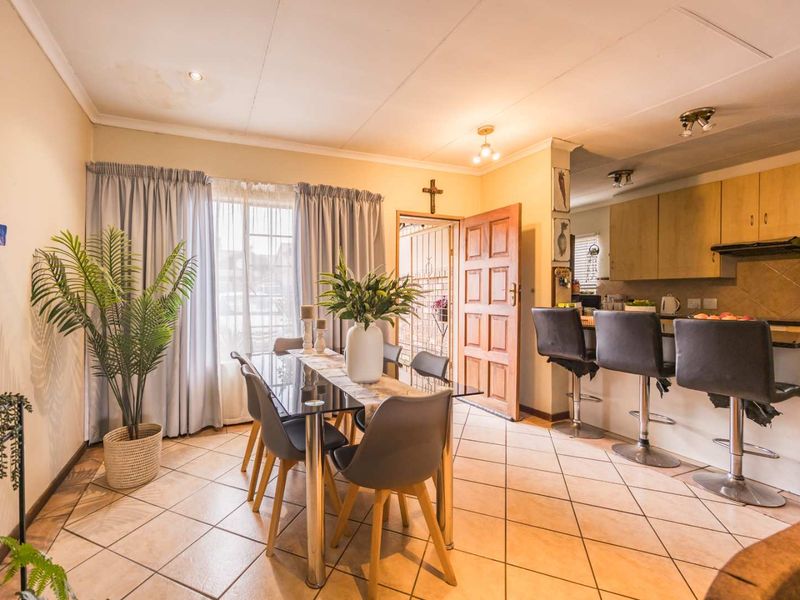 Open-plan dining and kitchen area featuring tiled flooring, breakfast bar seating, and built-in cabinetry, with visible ceiling water staining requiring attention.