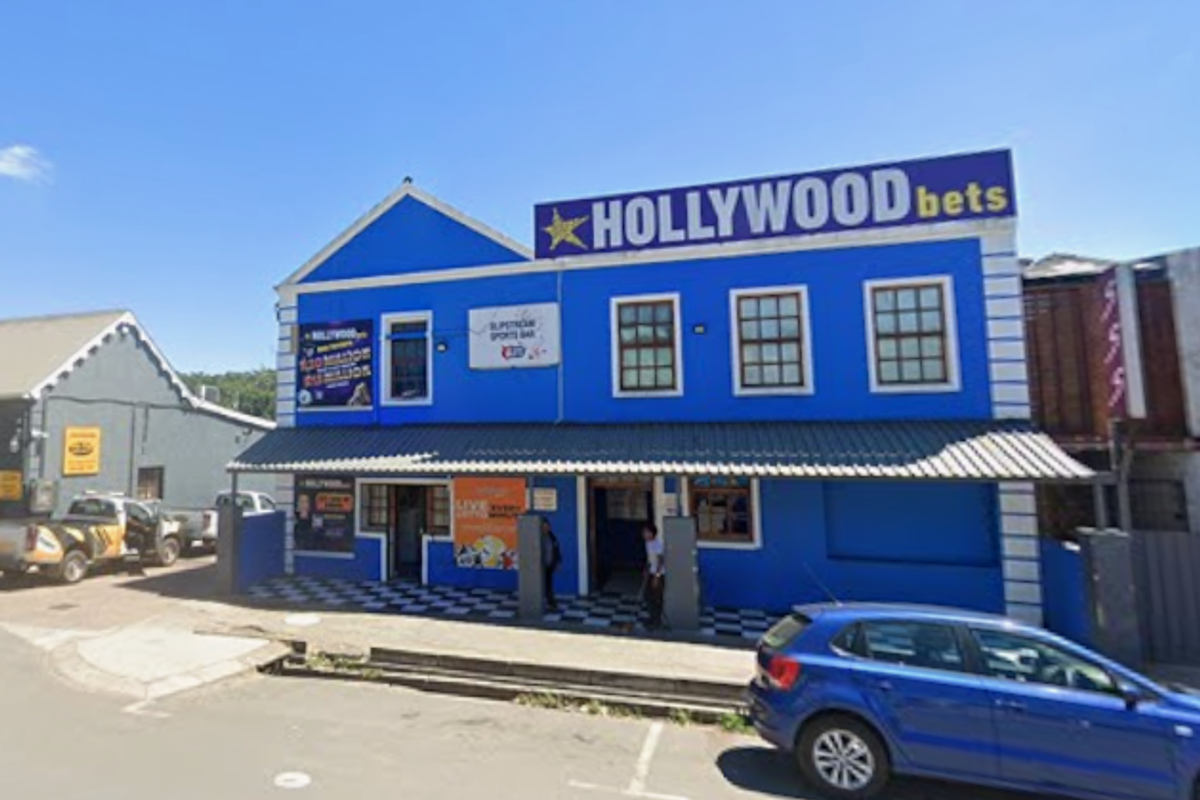 Front elevation of a commercial mixed-use building featuring a blue facade, metal roof awning, and prominent signage.