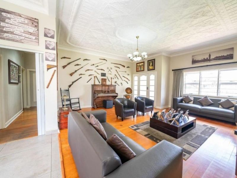 Spacious living room featuring original pressed metal ceilings, ornate ceiling rose, and polished hardwood flooring with access to the garden via french doors.