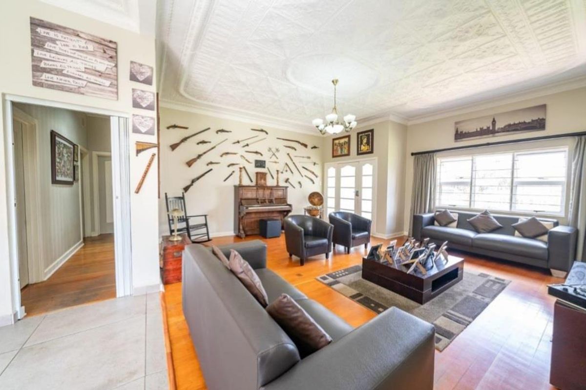 Spacious living room featuring original pressed metal ceilings, ornate ceiling rose, and polished hardwood flooring with access to the garden via french doors.