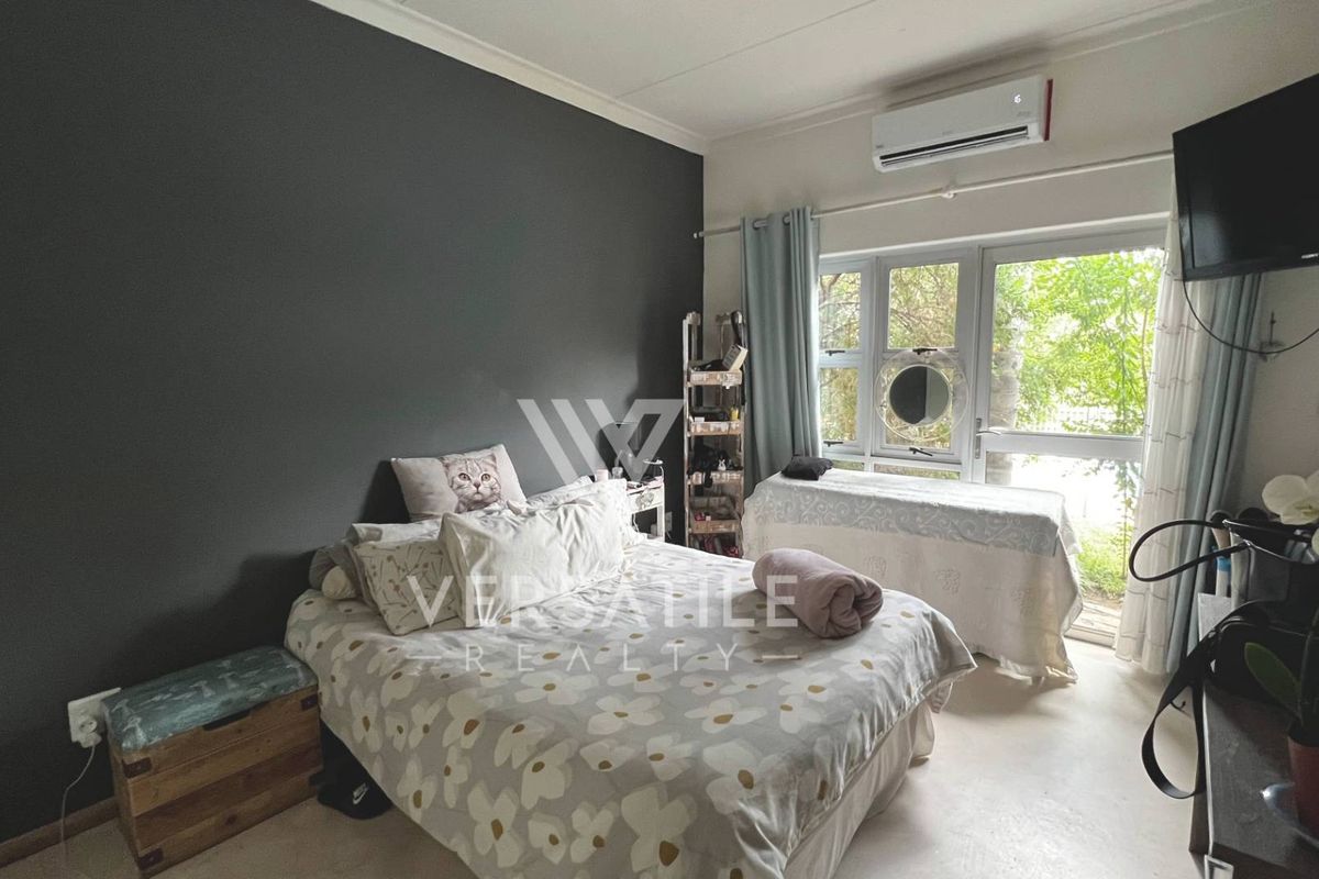 A bedroom featuring a dark accent wall, large windows providing natural light, and a wall-mounted air conditioning unit.