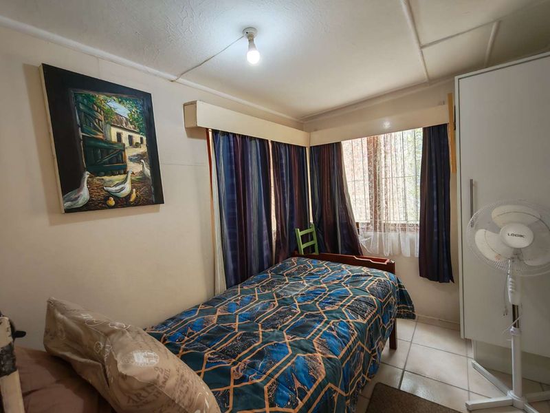A compact bedroom featuring tiled flooring and a built-in wardrobe, requiring some cosmetic updates to the ceiling and wall finishes.