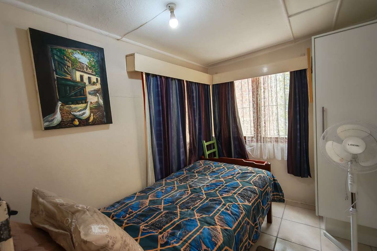 A compact bedroom featuring tiled flooring and a built-in wardrobe, requiring some cosmetic updates to the ceiling and wall finishes.