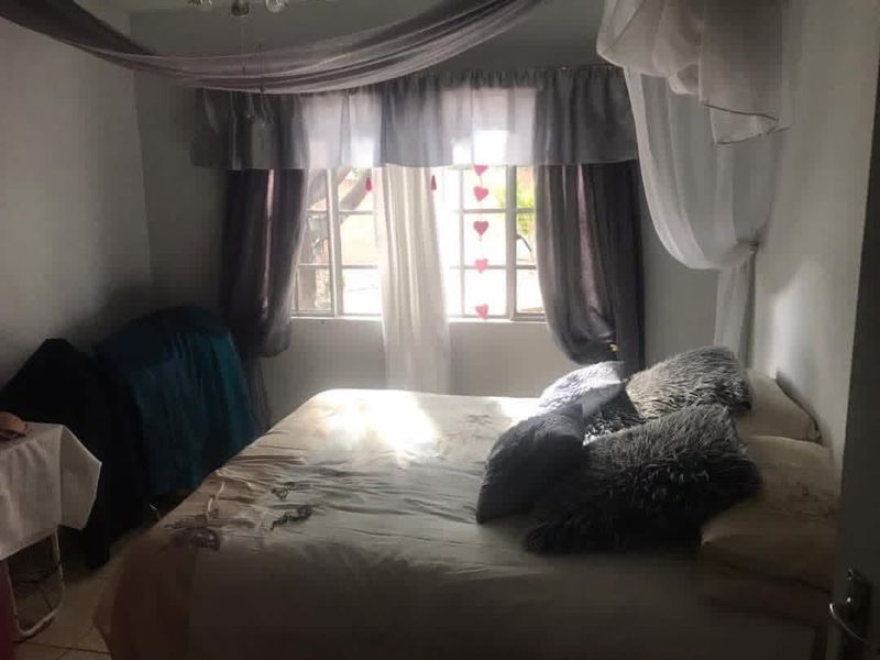 A bedroom featuring tiled flooring and a window with natural light, providing a functional space for rest.