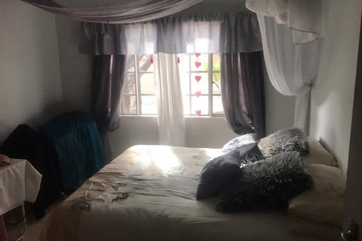 A bedroom featuring tiled flooring and a window with natural light, providing a functional space for rest.