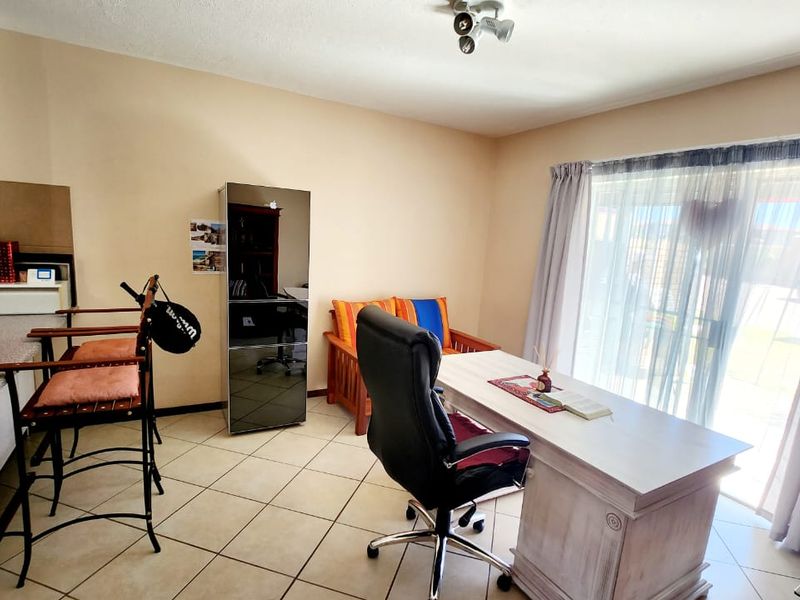 Open plan living area featuring tiled flooring, kitchen cabinetry with laminate countertops, and a sliding glass door providing access to the exterior.