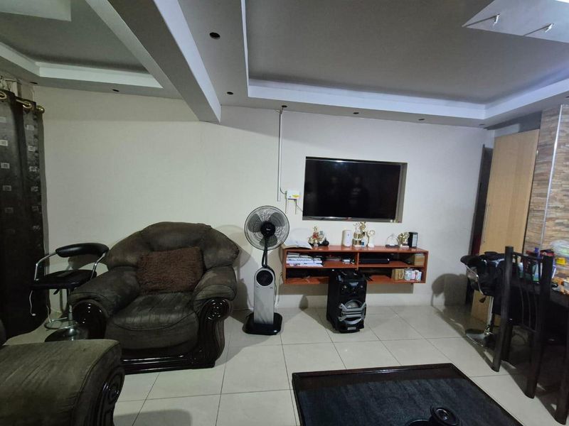 Living room featuring tiled flooring, recessed ceiling lighting, and a wall-mounted media shelf with a recessed television niche.