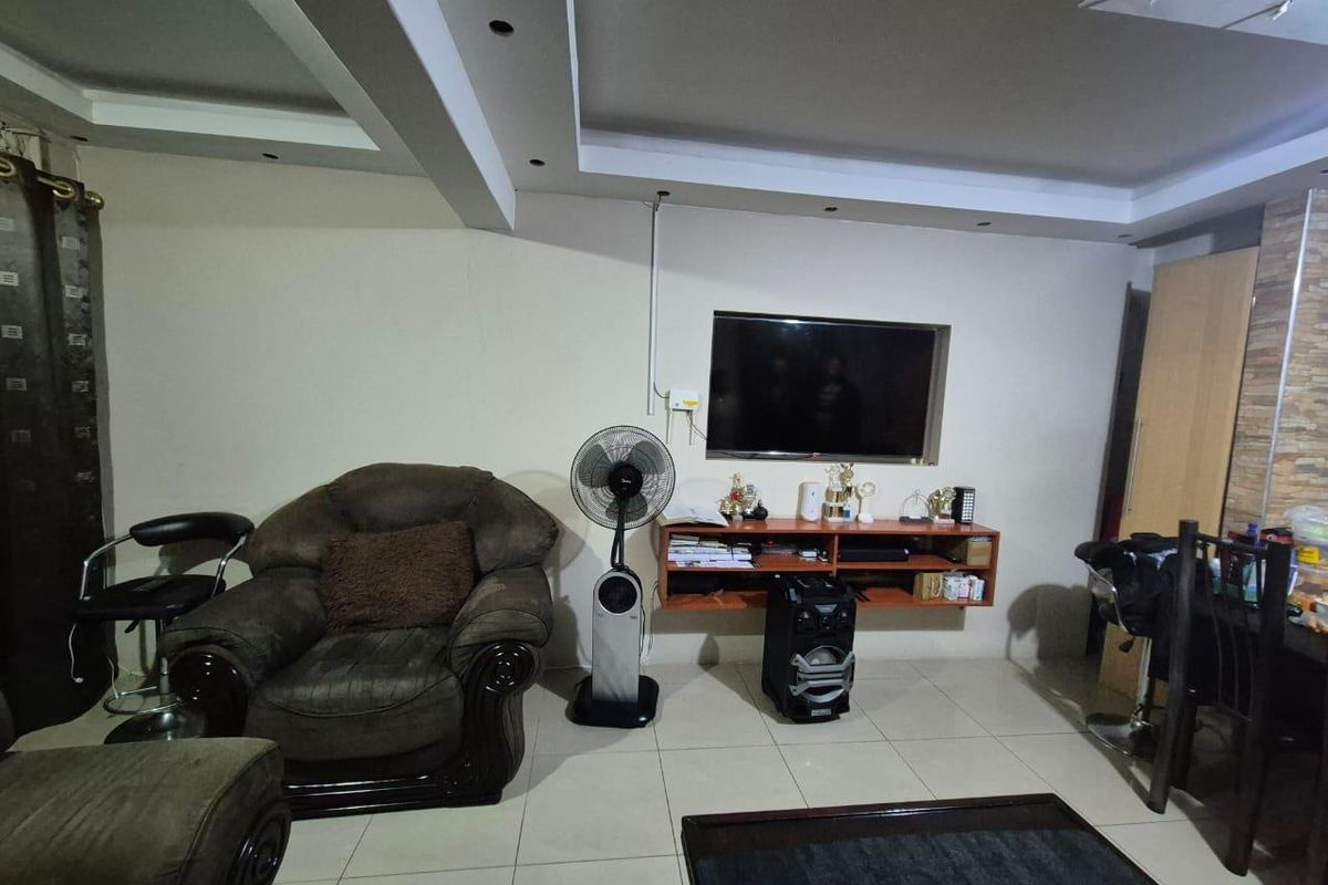 Living room featuring tiled flooring, recessed ceiling lighting, and a wall-mounted media shelf with a recessed television niche.