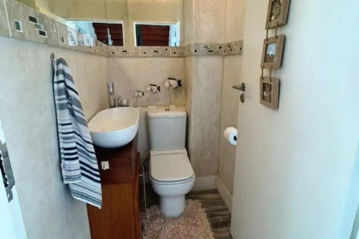 Compact bathroom featuring a vessel sink vanity, wall-mounted mirror, and standard toilet with wood-look flooring.
