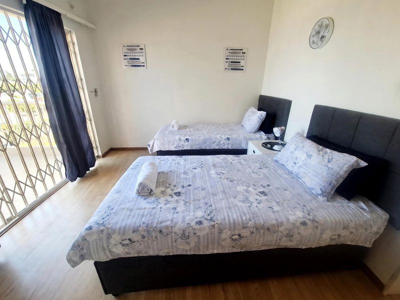 A bedroom featuring laminate flooring and a sliding door with a security gate, providing access to an outdoor area.