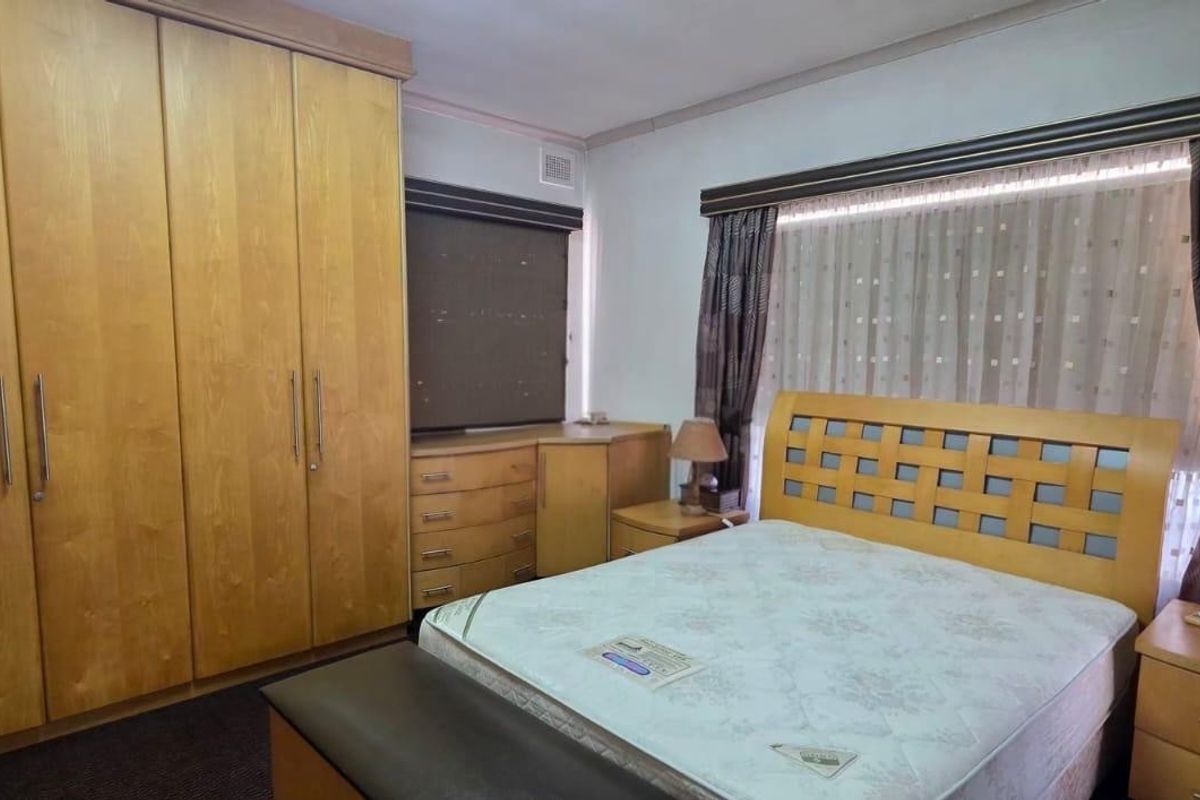 A bedroom featuring extensive built-in wooden cupboards and cabinetry, providing ample storage space with a neutral interior finish.