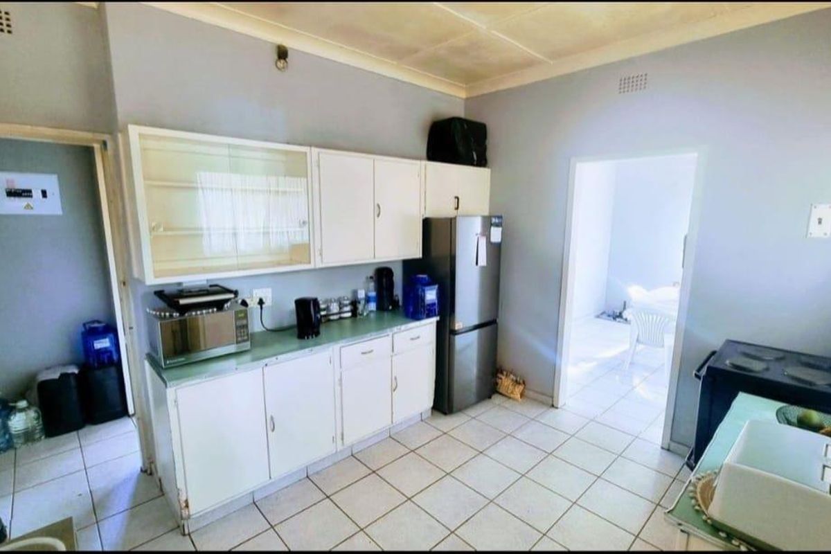 A functional kitchen featuring tiled flooring, built-in cabinetry, and a coved ceiling, offering a practical layout with potential for modern updates.