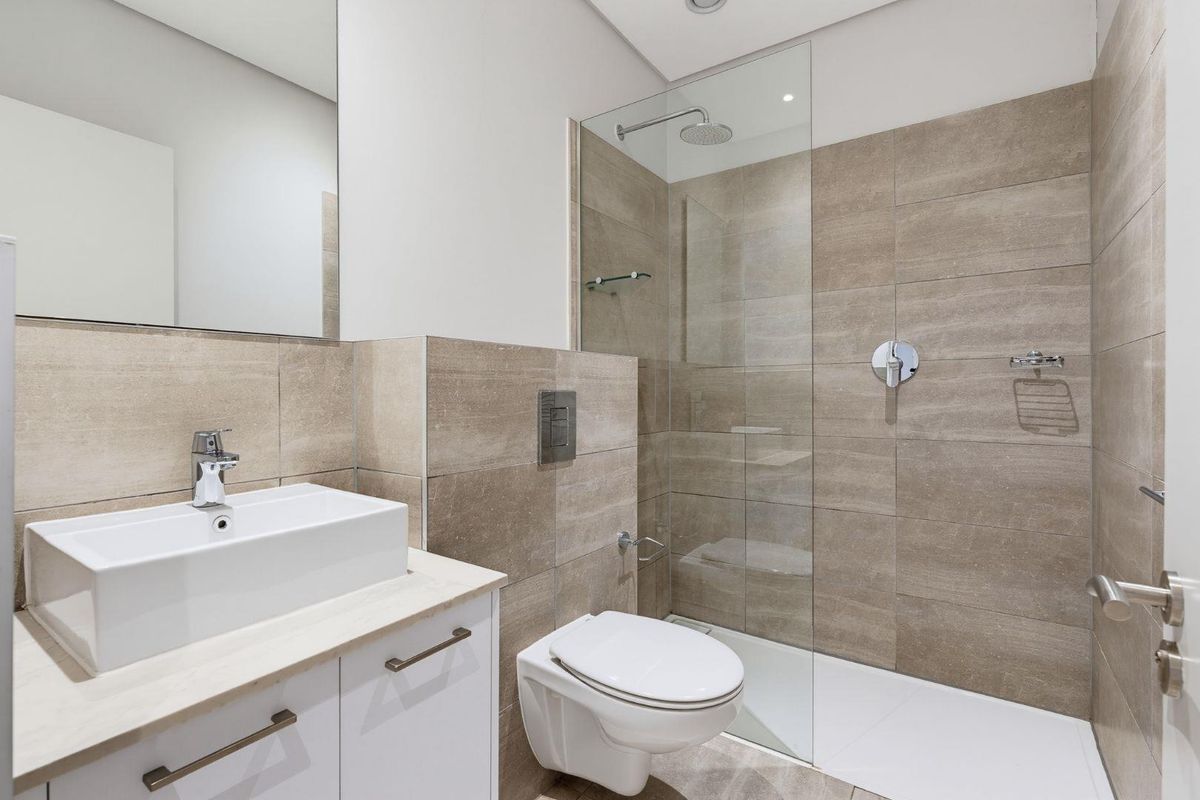 Modern bathroom featuring a walk-in shower with glass screen, wall-mounted toilet, and a sleek vanity with an above-counter basin.