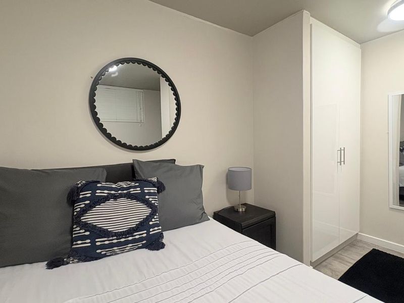 A well-maintained bedroom featuring a built-in wardrobe, neutral wall finishes, and modern laminate flooring.