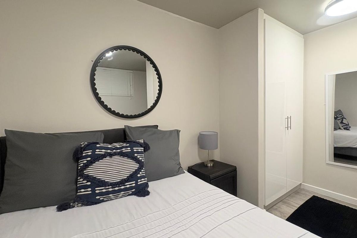 A well-maintained bedroom featuring a built-in wardrobe, neutral wall finishes, and modern laminate flooring.
