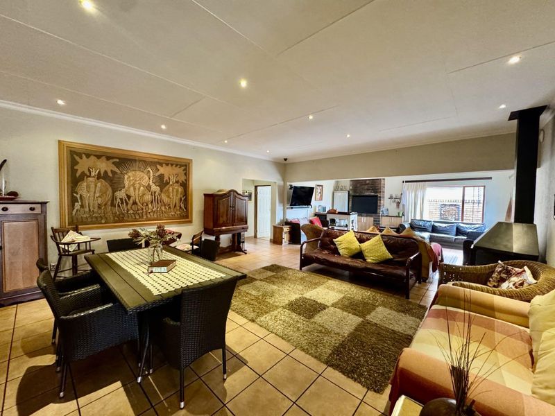 Spacious open-plan living and dining area featuring tiled flooring, recessed lighting, and a built-in fireplace, offering a versatile layout for family living.