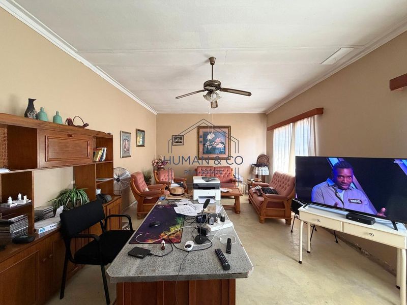 A spacious living area featuring a ceiling fan, crown molding, and built-in cabinetry, offering a versatile layout for relaxation or home office use.