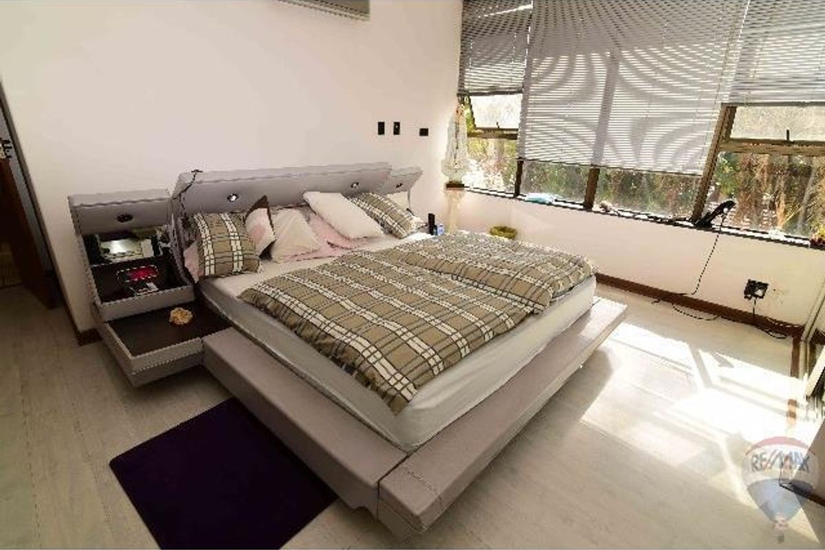 A bedroom featuring large windows with fitted blinds, light-toned flooring, and a wall-mounted air conditioning unit.
