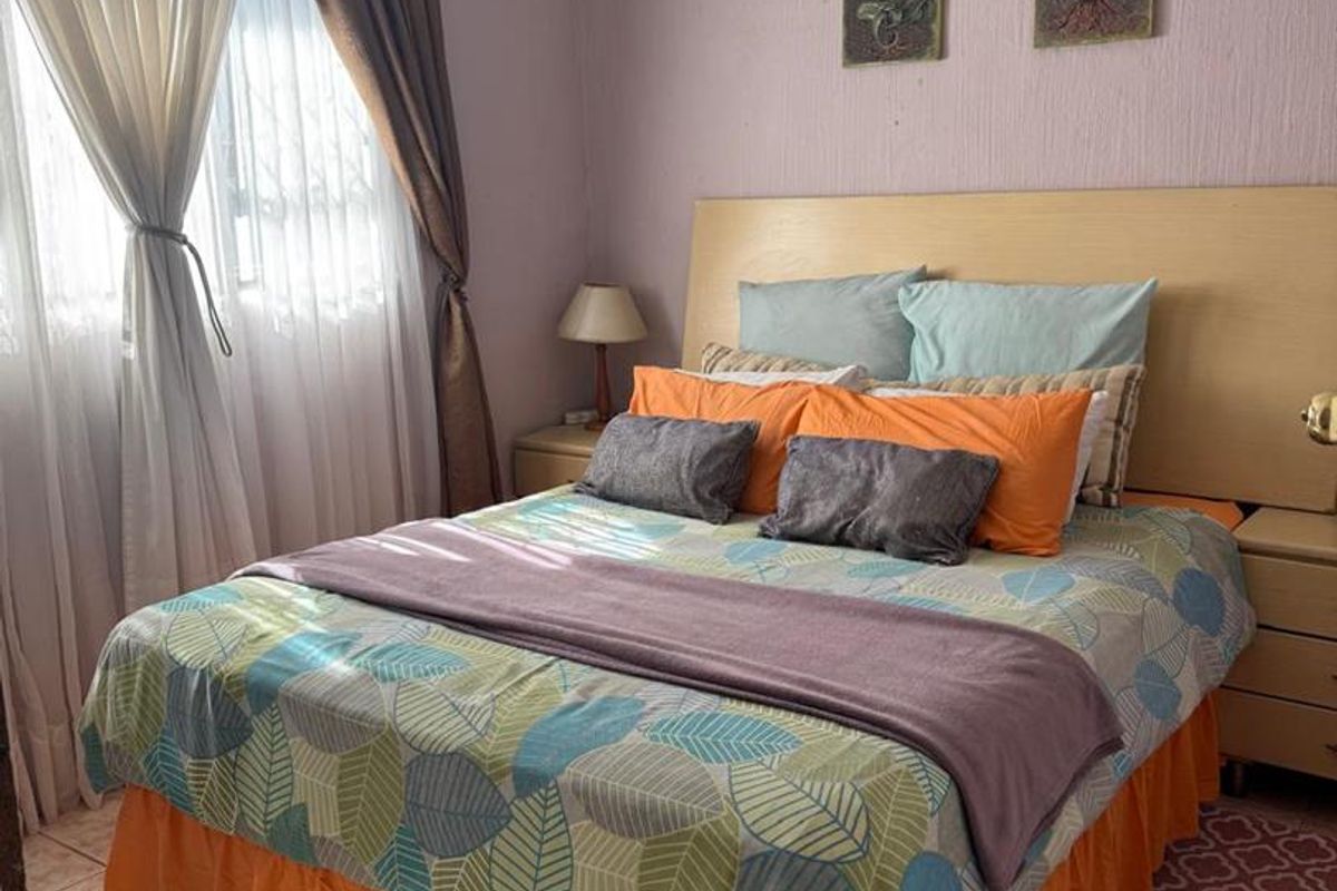 A bedroom featuring tiled flooring, a ceiling fan, and built-in headboard cabinetry.