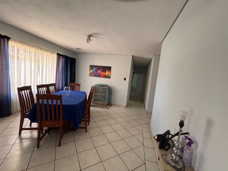 Dining area featuring tiled flooring and neutral wall tones, providing a functional space with direct access to the hallway.