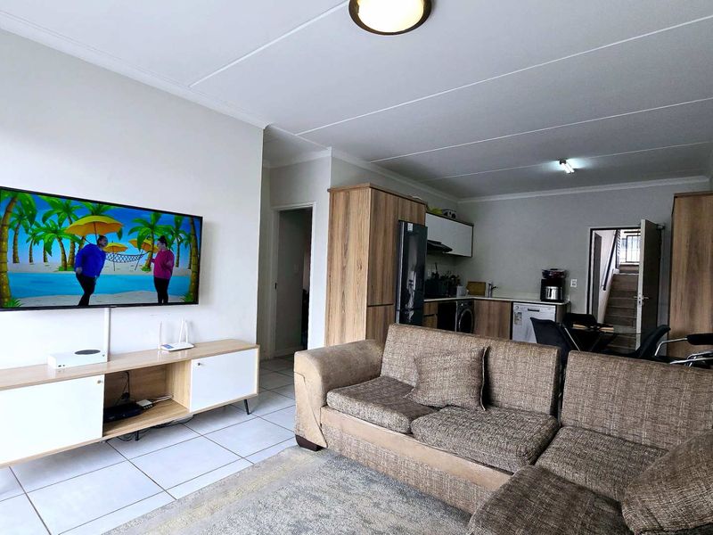 Open-plan living area featuring tiled flooring and an integrated kitchen with built-in cabinetry, creating a functional and connected living space.