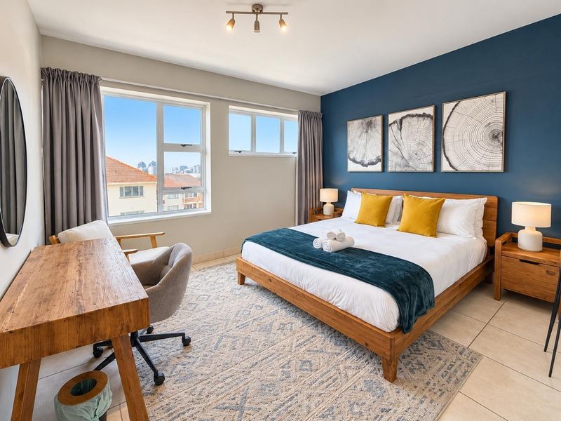 A well-lit bedroom featuring tiled flooring, large windows with natural light, and a feature wall, providing a comfortable and modern living space.