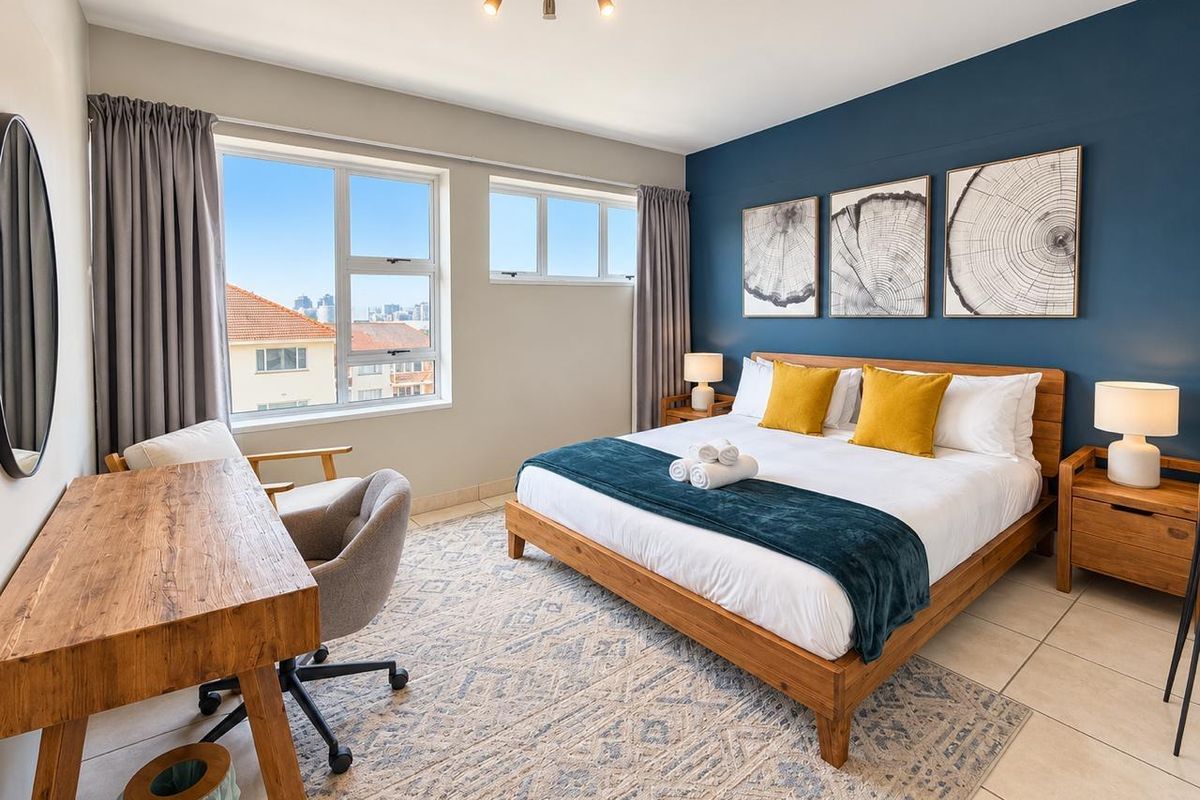 A well-lit bedroom featuring tiled flooring, large windows with natural light, and a feature wall, providing a comfortable and modern living space.