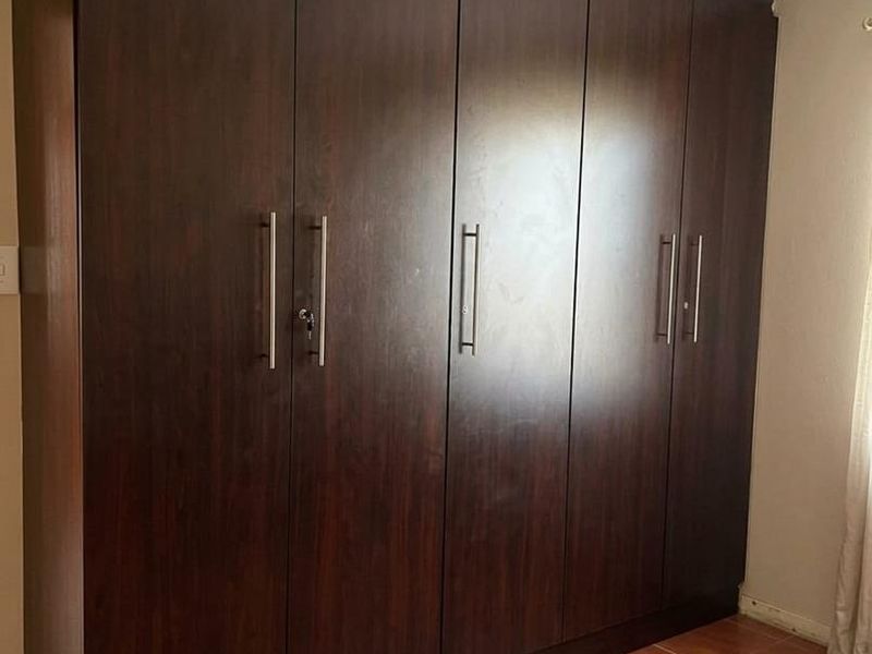 A bedroom featuring dark wood built-in cupboards and tiled flooring, providing ample storage space.