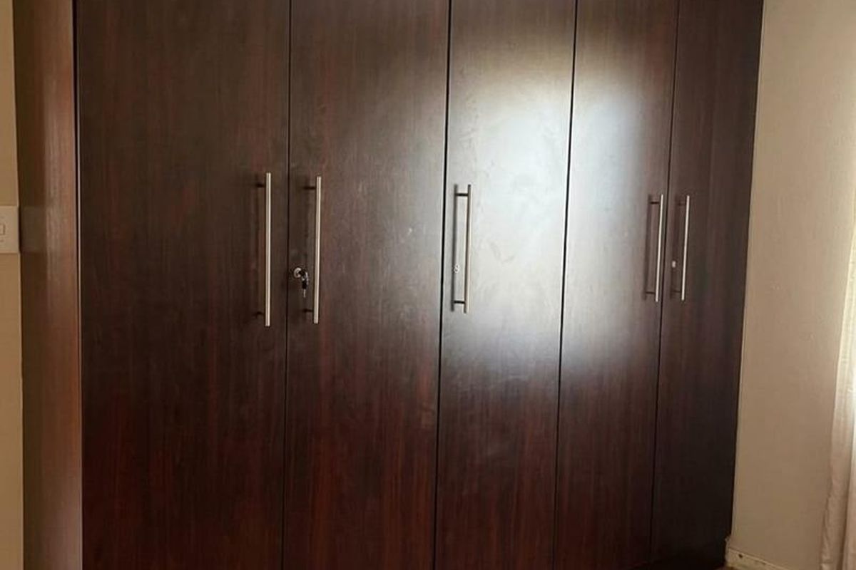 A bedroom featuring dark wood built-in cupboards and tiled flooring, providing ample storage space.