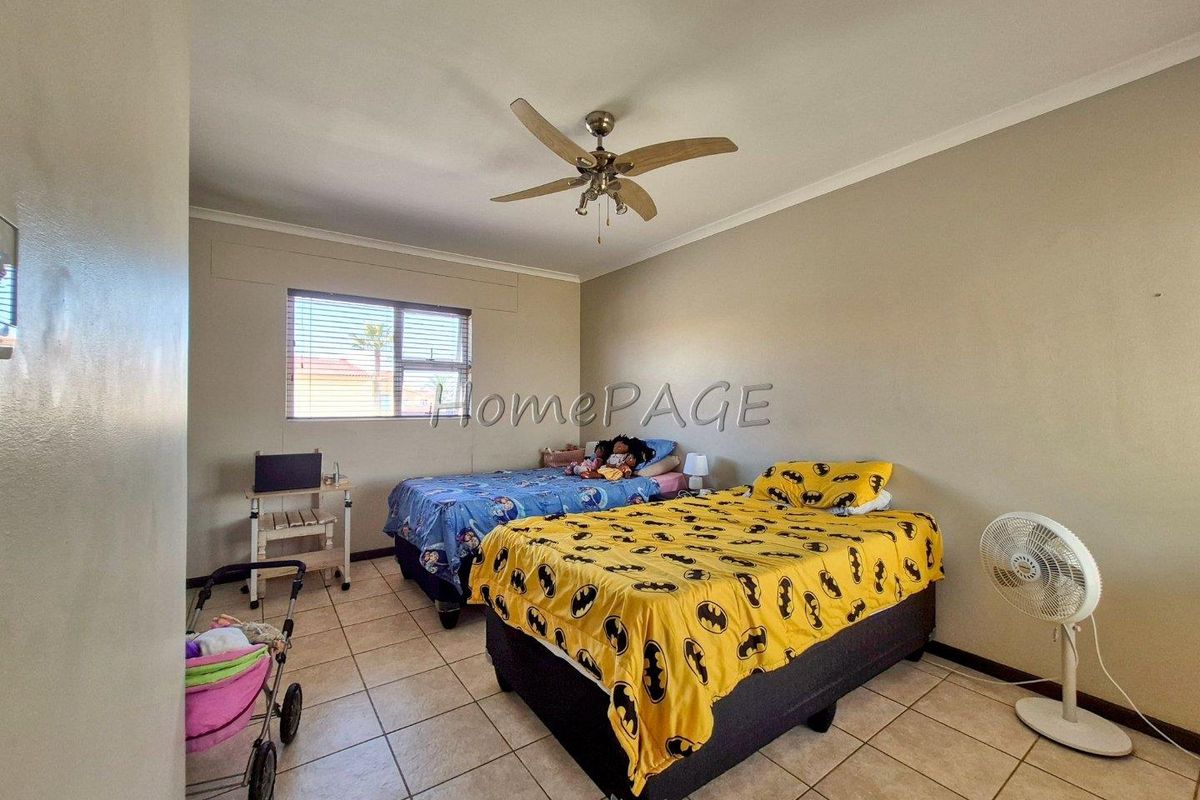 A bedroom featuring tiled flooring, a ceiling fan, and a window with blinds.