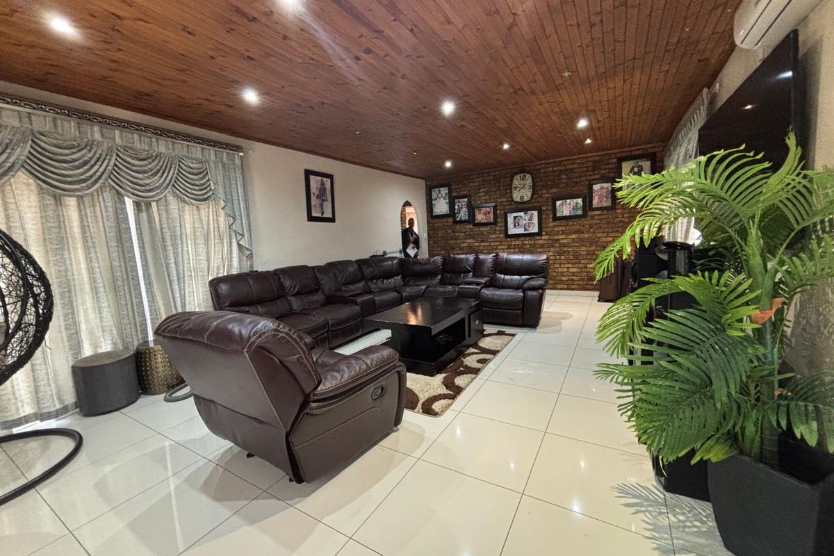 Spacious living room featuring a distinctive timber-clad ceiling, exposed brick feature wall, and polished porcelain floor tiles.